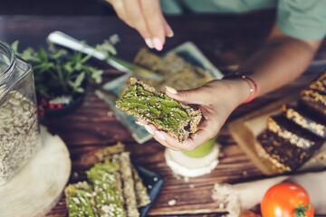 Woman hands spreading home made basil pesto on home baked gluten free bread