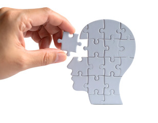 A hand places the final puzzle piece to complete a human head shape, symbolizing thought and understanding.