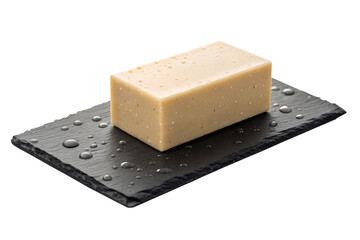 Close-up of a delicious rectangular bar of cheese with a pale yellow color and a rough texture presented on a black slate plate