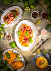 Summer appetizer with melon, prosciutto and lime illuminating the table