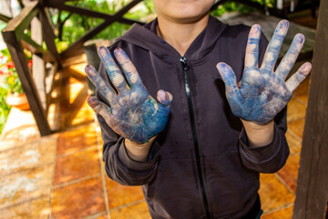 boy painted his hands , with black-blue paint, smiles, stands in gazebo, made by children, master class, creativity, art, close-up, handwork, design, brush,