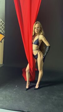 Dynamic studio pose by model in stylish outfit with dramatic backdrop