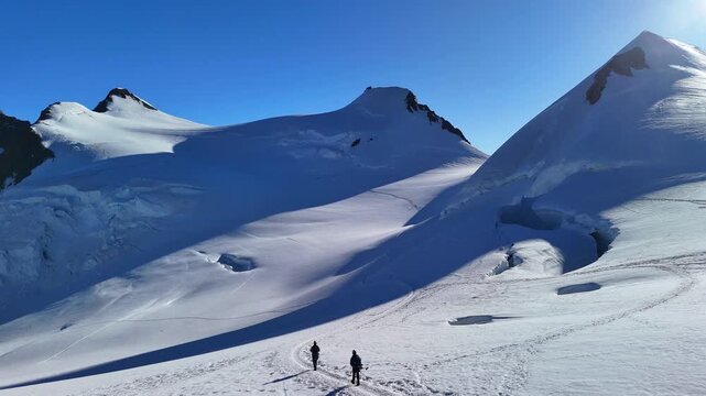 People trekking to Capanna Margherita, the highest mountain hut in Europe, located on Monte Rosa in the Italian Alps. Surrounded by glaciers, snowy peaks and alpine landscape. Italy