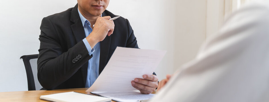 Employer or recruiter holding reading a resume during his profile of candidate, employer in suit is conducting a job interview - Powered by Adobe