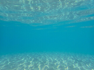 Light filtering down through blue water. Underwater sunlight in deep sea. Light viewed from blue abyss. Underwater sunlight shining deep with ripples on wave surface ocean ray, Mediterranean sea.
