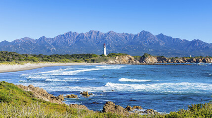 Scenic coastal view featuring lighthouse, mountains, and waves crashing on shore, evoking tranquility and natural beauty