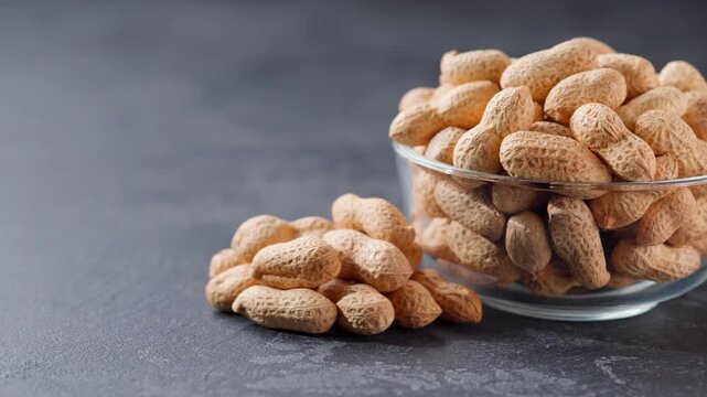organic peanuts in a glass plate and scattered on a black stone table.
peanuts in a clear glass bowl on a black kitchen table.