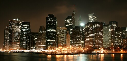 Naklejka premium City skyline at night with illuminated buildings.