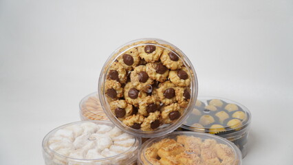 Homemade chocolate thumbprint cookies with peanut sprinkles arranged in a clear plastic jar, isolated on a clean white background. Perfect for dessert packaging mockups or food blogs