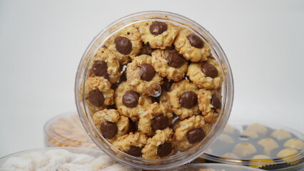 Homemade chocolate thumbprint cookies with peanut sprinkles arranged in a clear plastic jar, isolated on a clean white background. Perfect for dessert packaging mockups or food blogs