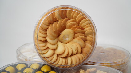 High-resolution horizontal photo of Lidah Kucing butter cookies stacked neatly in a clear plastic jar, isolated on a white background. Ideal for snack packaging, food blogs, and Eid-related visuals