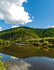 Naklejka premium Scenic river reflecting a hillside landscape