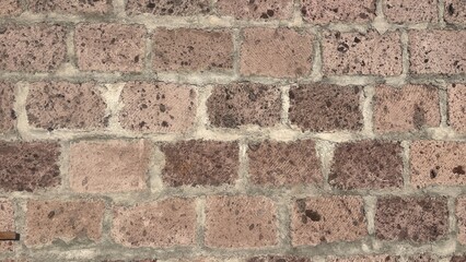 Close-up view of a rustic brick wall made of traditional Armenian tuff stone, showcasing a rich and authentic texture. The bricks vary in natural shades of pink.