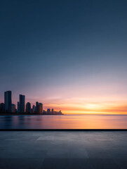 Fototapeta premium City skyline silhouette at sunset over calm water, serene urban landscape with orange sky 