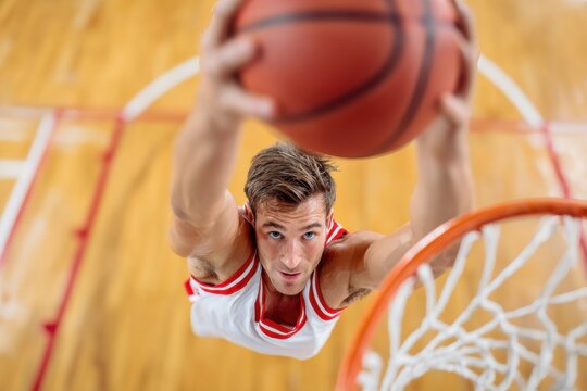 Basketball player dunking during a match in a covered court - Powered by Adobe