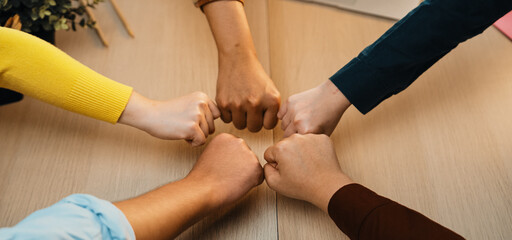 A vibrant scene depicting diverse hands engaging in a fist bump over a wooden table, illustrating...