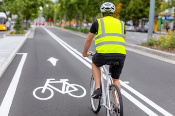 Cyclist wearing safety vest riding bicycle in dedicated lane