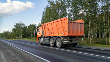 Dumper truck on the road. Construction equipment is driving on the highway. A car with a body to carry loose material. © yaviki