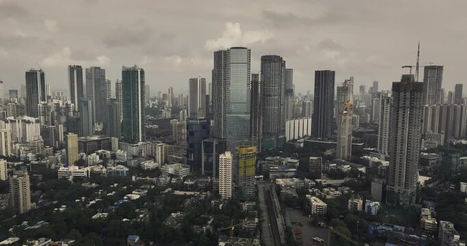 Cinematic aerial view of the Mumbai city skyline of Maharashtra, India, during the monsoon season, with dramatic clouds and top shots of moving cars, captured from above the clouds.