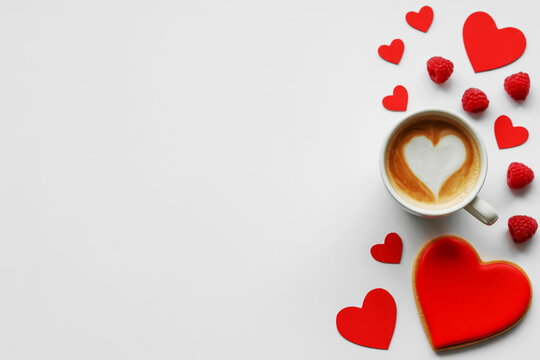 Cozy morning coffee with heart shaped latte art and romantic red hearts on a white background - Powered by Adobe