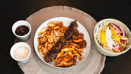 A beautifully arranged platter of grilled chicken shish, lamb shish, and doner kebab, served with vibrant sauces on the side. Elegant plating for food photography, menus, and promoting healthy, protei