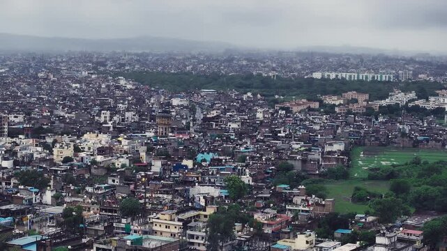 Aerial view of Bhopal city during the monsoon season, showcasing its urban landscape surrounded by lush greenery, water bodies, and mist-covered hills.