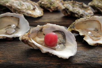 Fresh sea bivalve oysters are laid out on a wooden table. Oysters are a dietary, sports food and affect human health and longevity. Pearl formation is used in the jewelry industry.