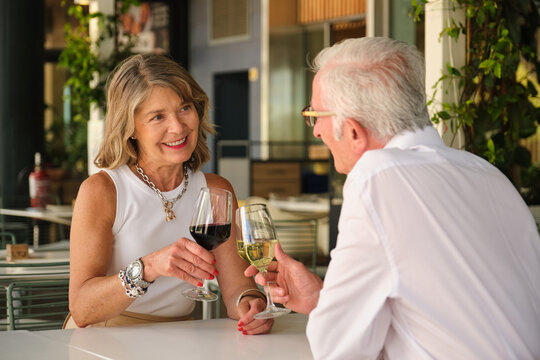 Happy retired couple enjoying a romantic moment, drinking wine at an outdoor restaurant