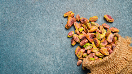 Linen bag with pistachios. Salted nuts. On a gray concrete background. Top view, free space for text.