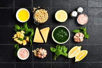 Pesto sauce and ingredients. On a black stone background. Creative photo. Top view.