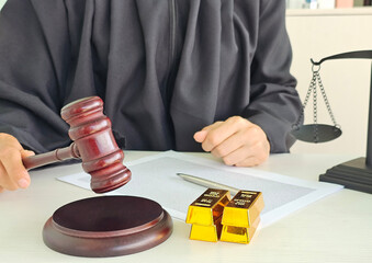 Judge making a ruling with gold bars and scales of justice