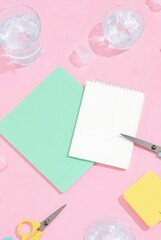 Fresh summer aesthetic with ice water, notepad, scissors, and colorful stationery on pink backdrop
