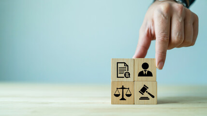 Fingers arranging wooden blocks with legal icons symbolizing justice law and compliance in a business context