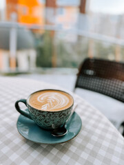 Warm cup of coffee on a checkered table at a cozy outdoor cafe during morning hours
