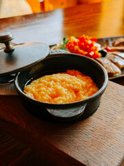 Delicious traditional dish served in a cast iron pot with fresh toppings at a rustic setting