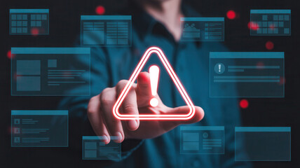 Man's finger touching glowing digital warning sign, showcasing data breach, cybersecurity threat, and online safety concerns, modern tech concept
