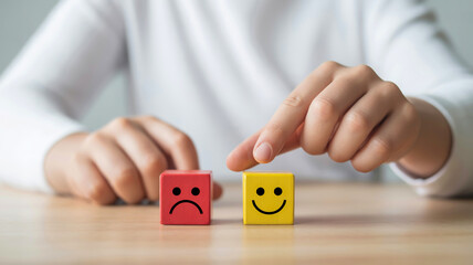 Person s hands choosing between sad and happy face blocks representing mood and emotion