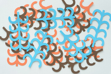 machine-cut decorative paper shapes with linear and curve cutouts in blue brown and orange arranged on blank paper