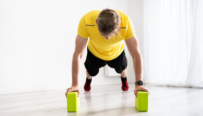 Young Man Doing Routine Sport At Home With Yoga Blocks
