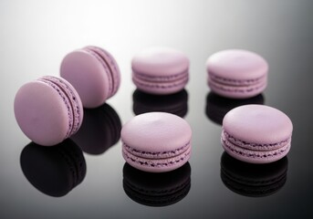 Six delicate pink macarons with cream filling arranged on a glossy dark surface