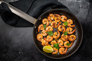 Fried Shrimps Prawns with garlic and butter in a skillet. Black background. Top view