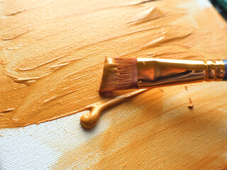 A golden paintbrush applies textured gold paint on a canvas, showcasing artistic creativity and craftsmanship. Perfect visual for concepts of art, painting, and artistic expression.