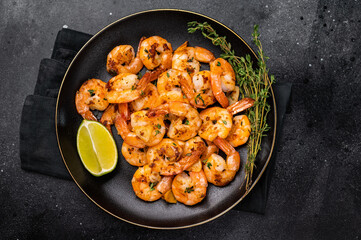 Grilled spicy Shrimps Prawns with garlic and lime in a plate. Black background. Top view