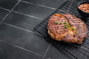 Grilled Rib eye steak on black rack, roasterd prime dry aged beef meat. black background. top view
