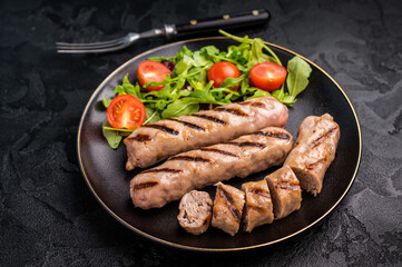 Salad with grilled beef and pork sausages on plate. black background. top view
