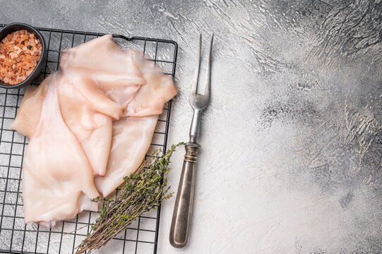 Close up of tender raw squid showcasing its smooth texture, ideal for culinary creativity and seafood lovers. grey background. top view