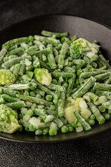 Frozen green vegetables green peas, broccoli, string beans, kohlrabi kale tasty snack fresh food background on the table rustic food top view copy space keto and paleo diet vegan and vegetarian food