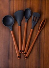 stylish orange handled kitchen utensils with black silicone heads on wooden surface display