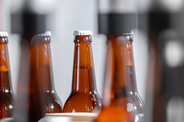 Beer bottling process: close-up of amber glass bottles in brewery production line