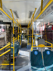 Bright interior of modern bus with patterned seats and yellow handrails for passenger comfort  © Alena